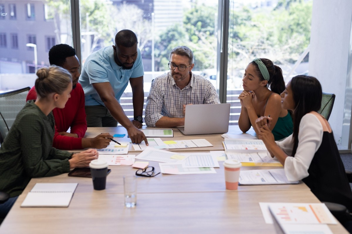 Business team collaborating on strategy with laptops, charts, and planning materials